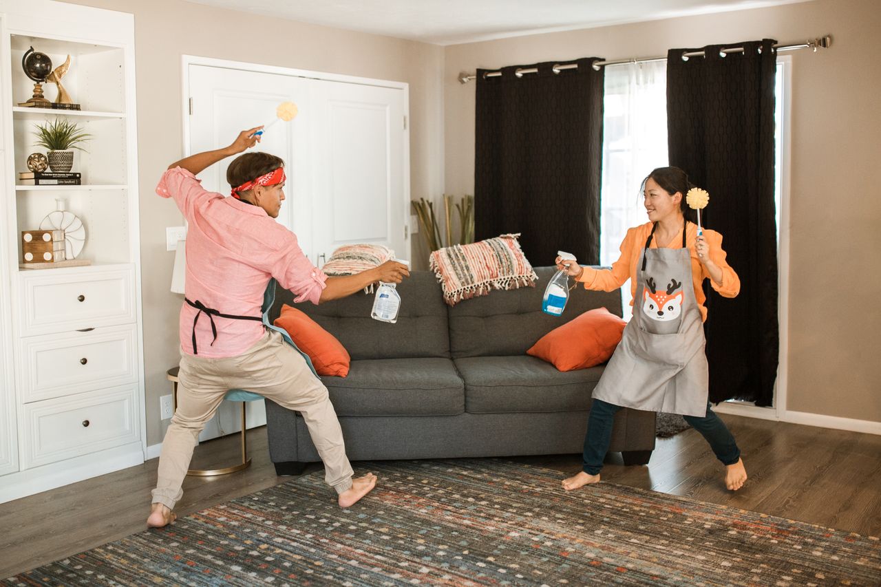 Crafting Captivating Headlines: Your awesome post title goes here A joyful couple engages in a playful cleaning fight in their living room, showcasing light-hearted domestic life.